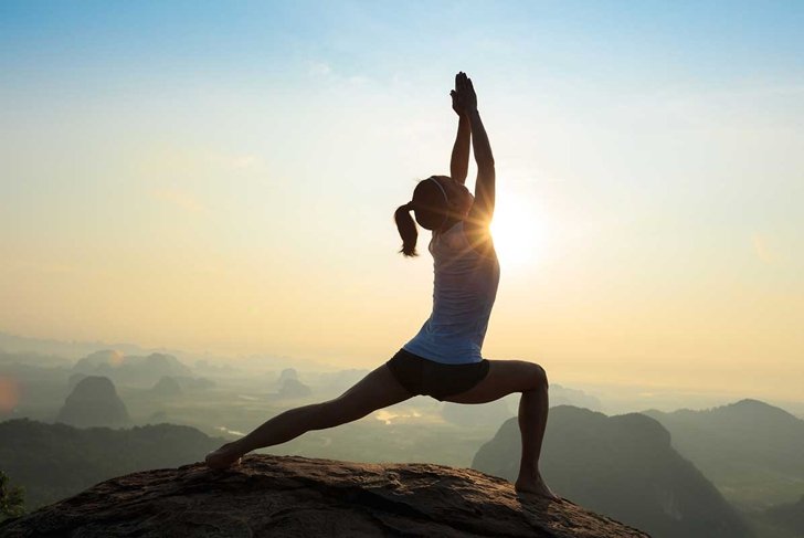 young fitness woman meditating on sunrise mountain peak