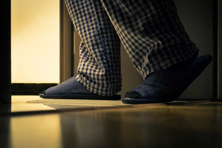 Adult man in pajamas walks to a bathroom at the night. Men's healths concept