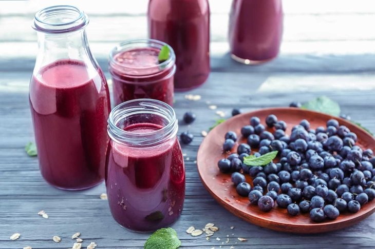 Glass bottles with acai juice and berries on plate